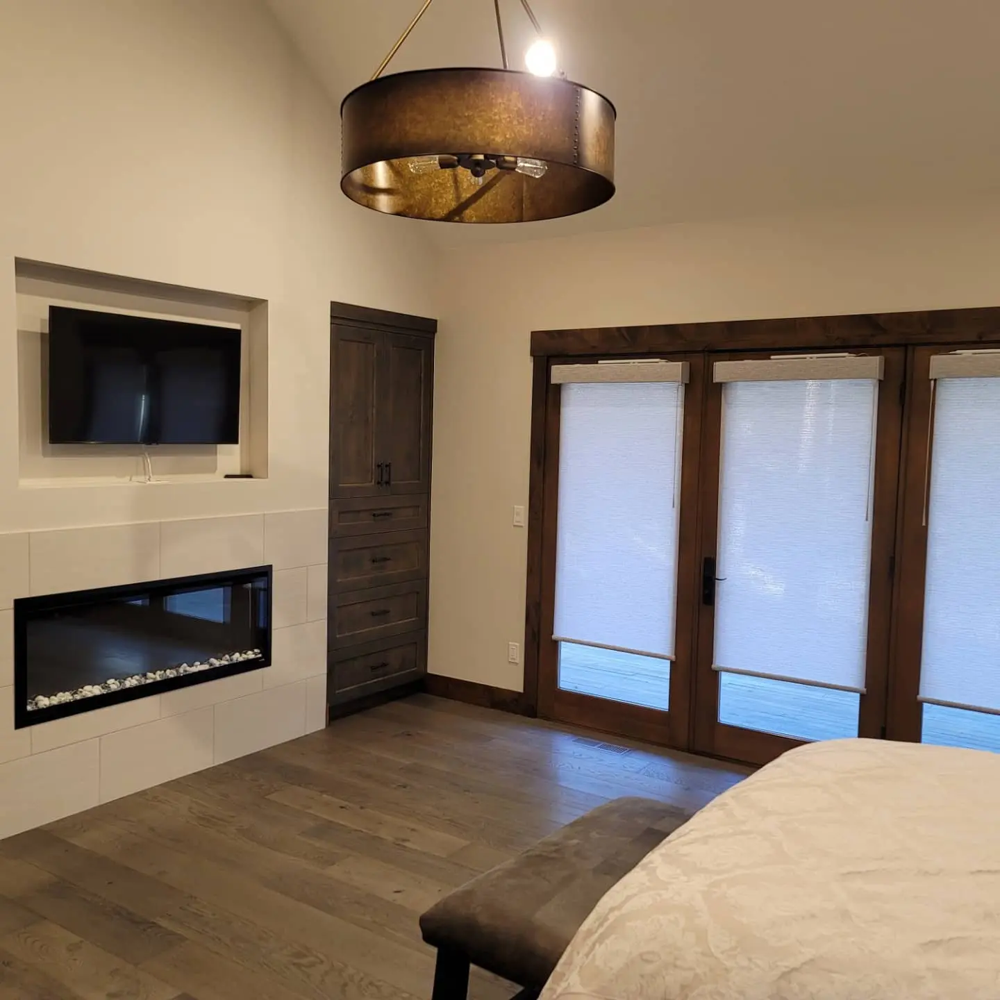 Sunriver master suite with a modern white-tiled fireplace, custom built-ins, and direct deck access.