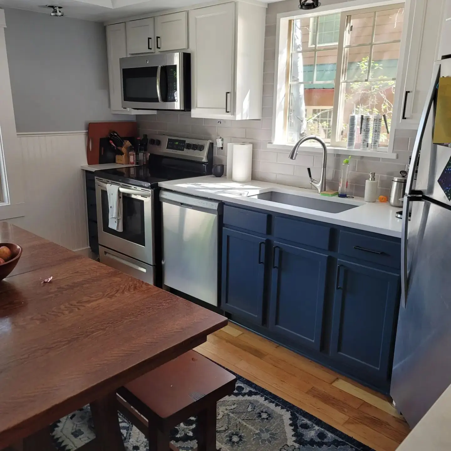Final look of a Bend kitchen transformation featuring two-tone cabinets, white subway tile, and wood floors.