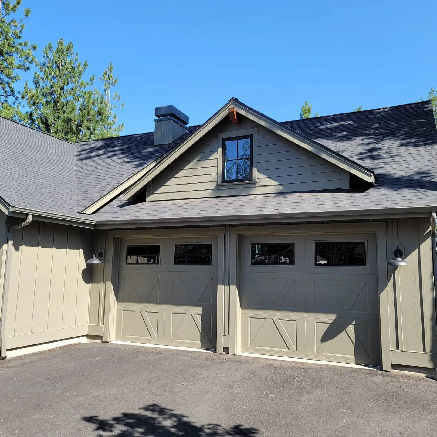 Carriage-style garage doors on a residential home in Sisters, OR, showing sharp trim lines and a professional finish.