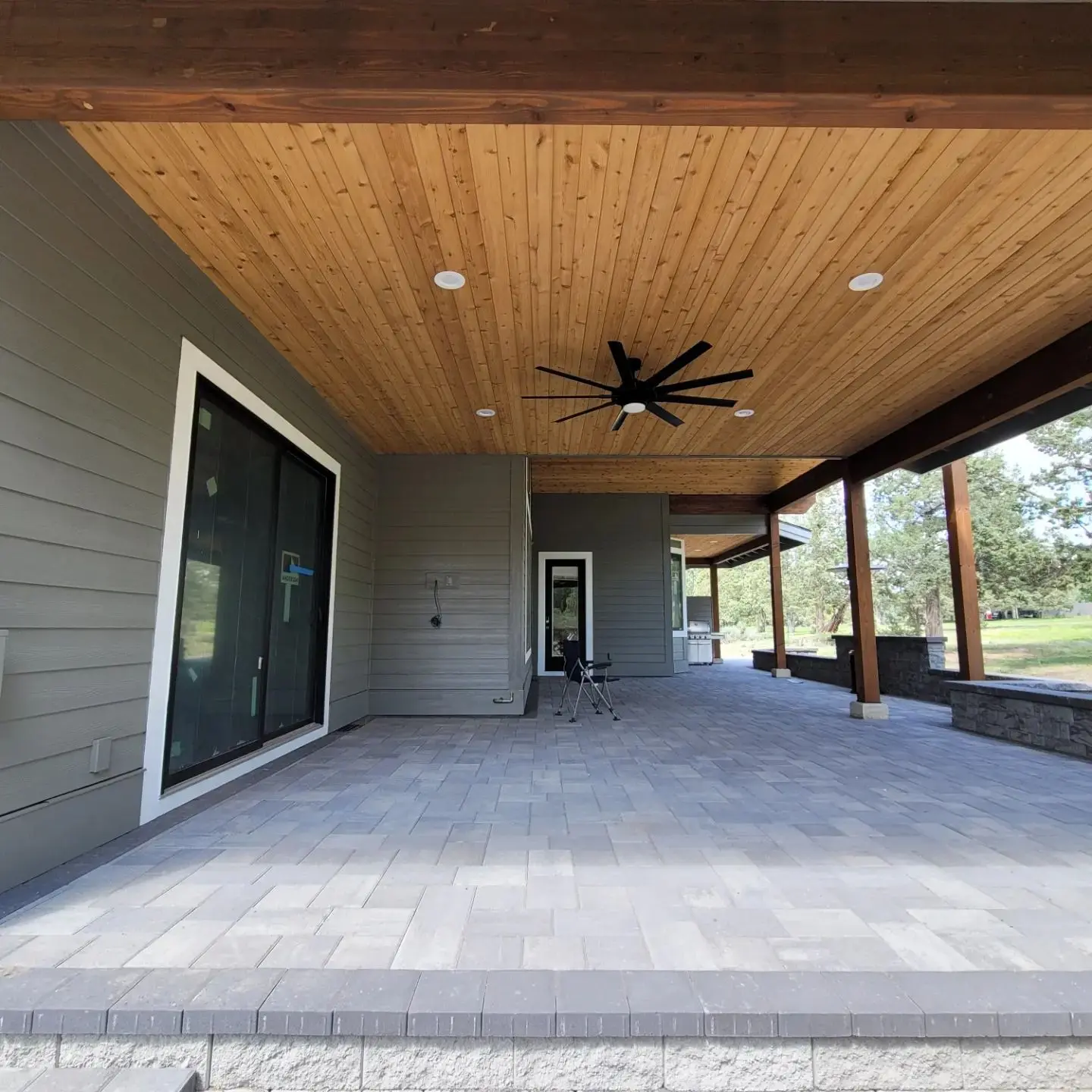 Large covered patio in Redmond featuring a natural tongue-and-groove wood ceiling and modern black ceiling fan.