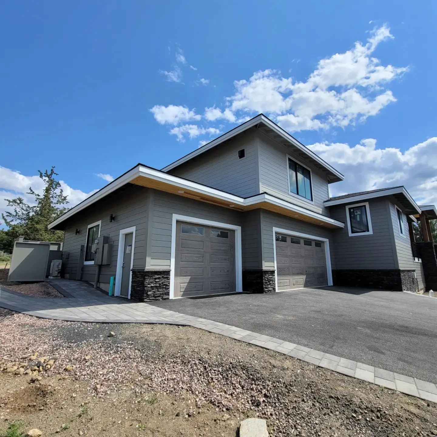 View of a modern three-car garage in Redmond featuring gray doors and stone base accents.