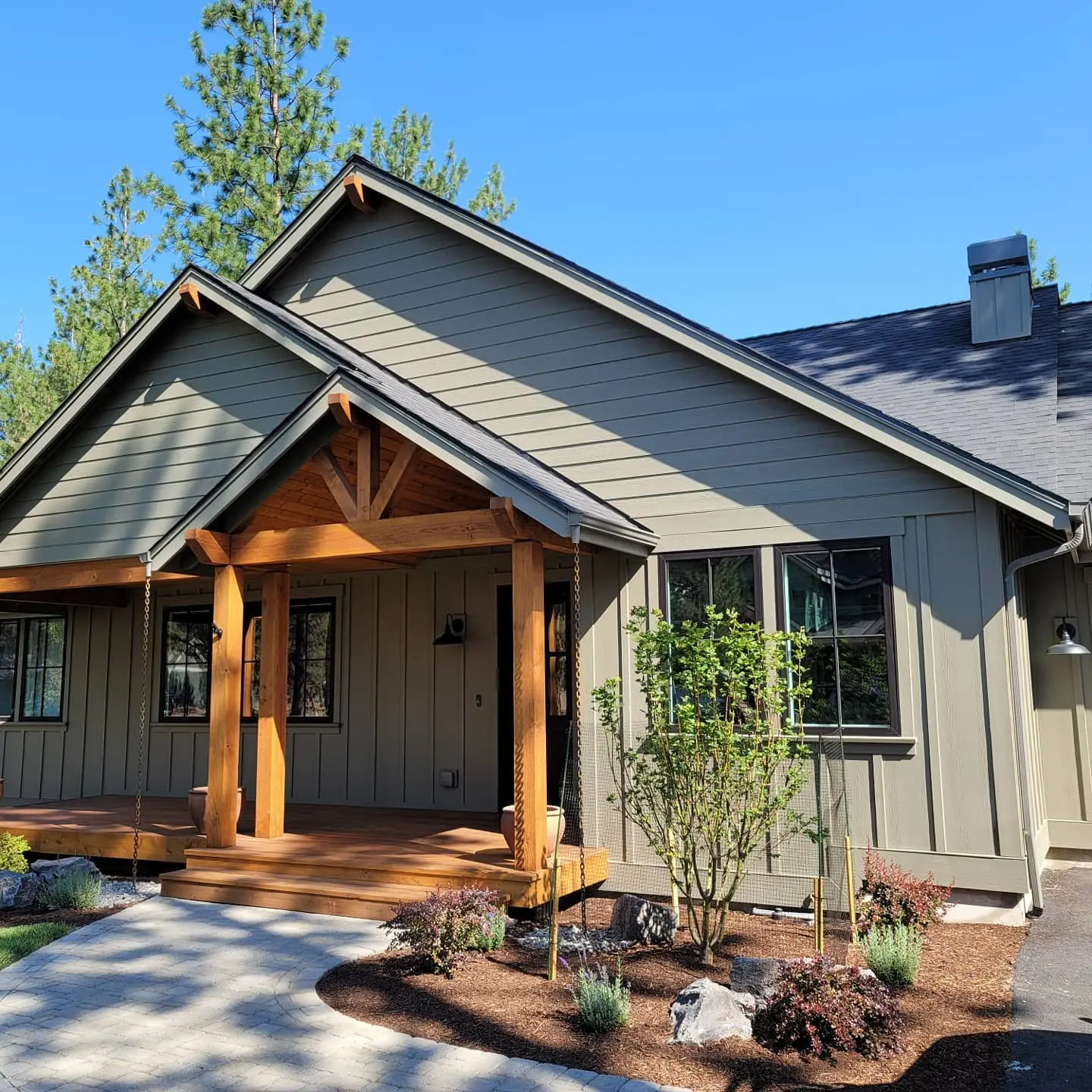 Timber-frame entry with natural wood beams finished with PPG ProLuxe stain and a black door in Sisters, OR.